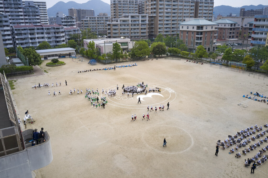 グランドに集まって人文字を形成する様子を写真撮影